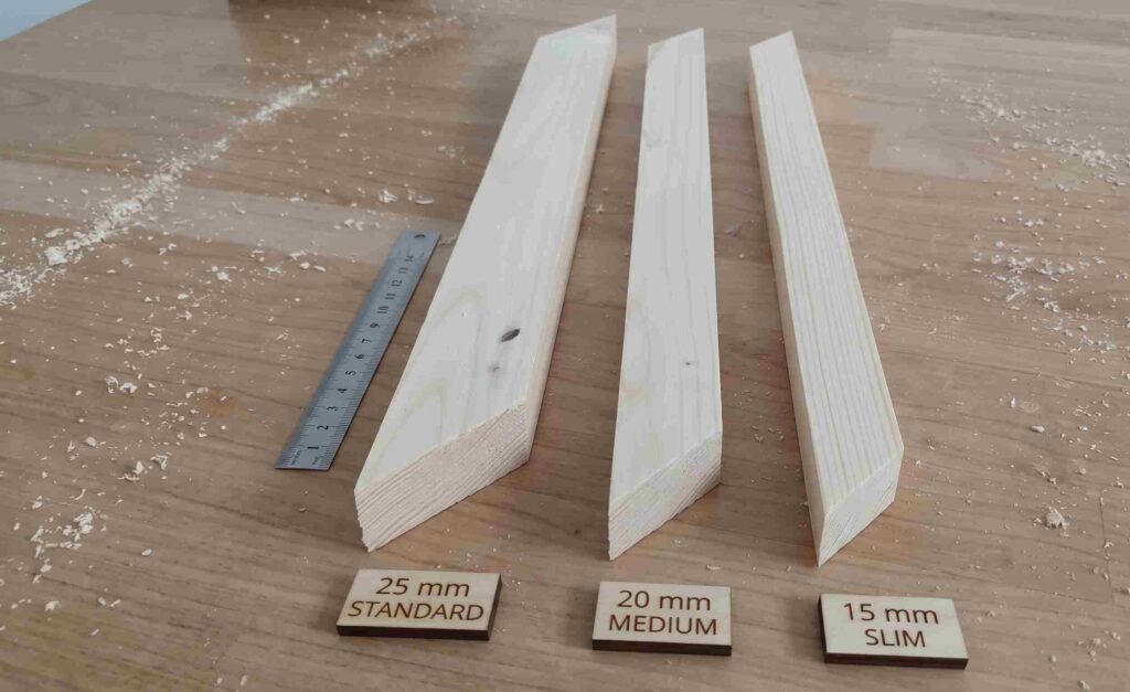 Three wooden stretcher bars for canvas frames placed side-by-side on a wood surface, labeled 25mm standard, 20mm medium, and 15mm slim, accompanied by a metal measuring scale.